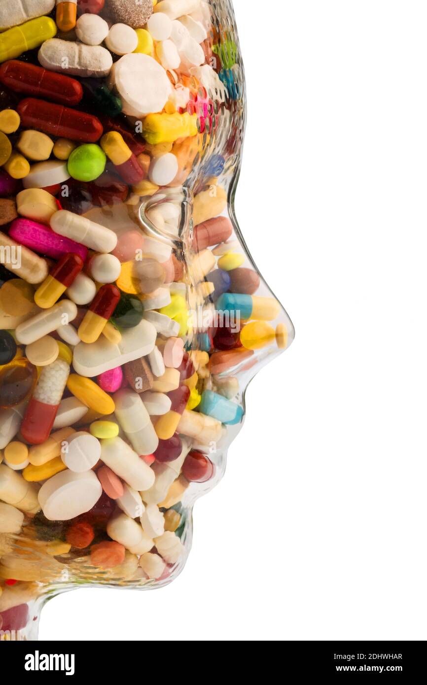 Ein Kopf aus Glas mit vielen Tabletten gefüllt. Simbolphoto für Medizamente, Mißbrauch und Tablettensucht. Banque D'Images