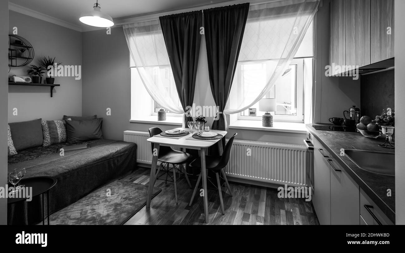 Intérieur moderne de la cuisine dans un studio de luxe. Table et chaises en bois. Canapé confortable avec coussins. Noir et blanc. Banque D'Images