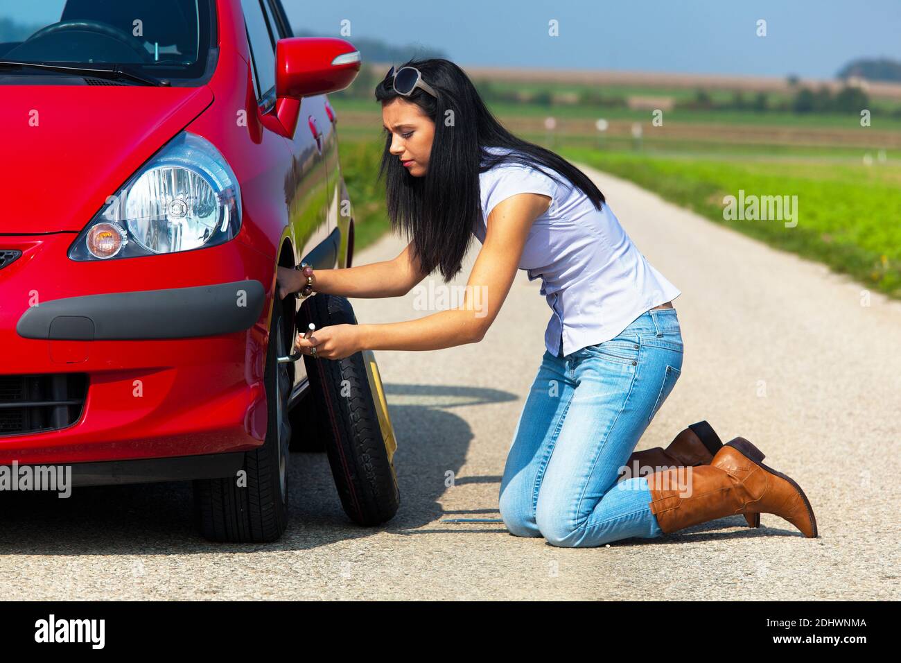 Junge Frau mit einer Reifenpanne am Auto Banque D'Images