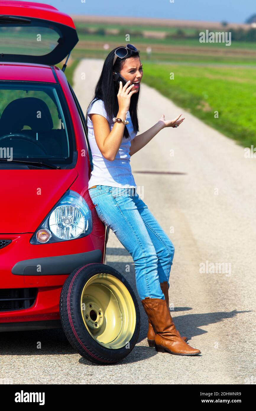 Junge Frau mit einer Reifenpanne am Auto Banque D'Images