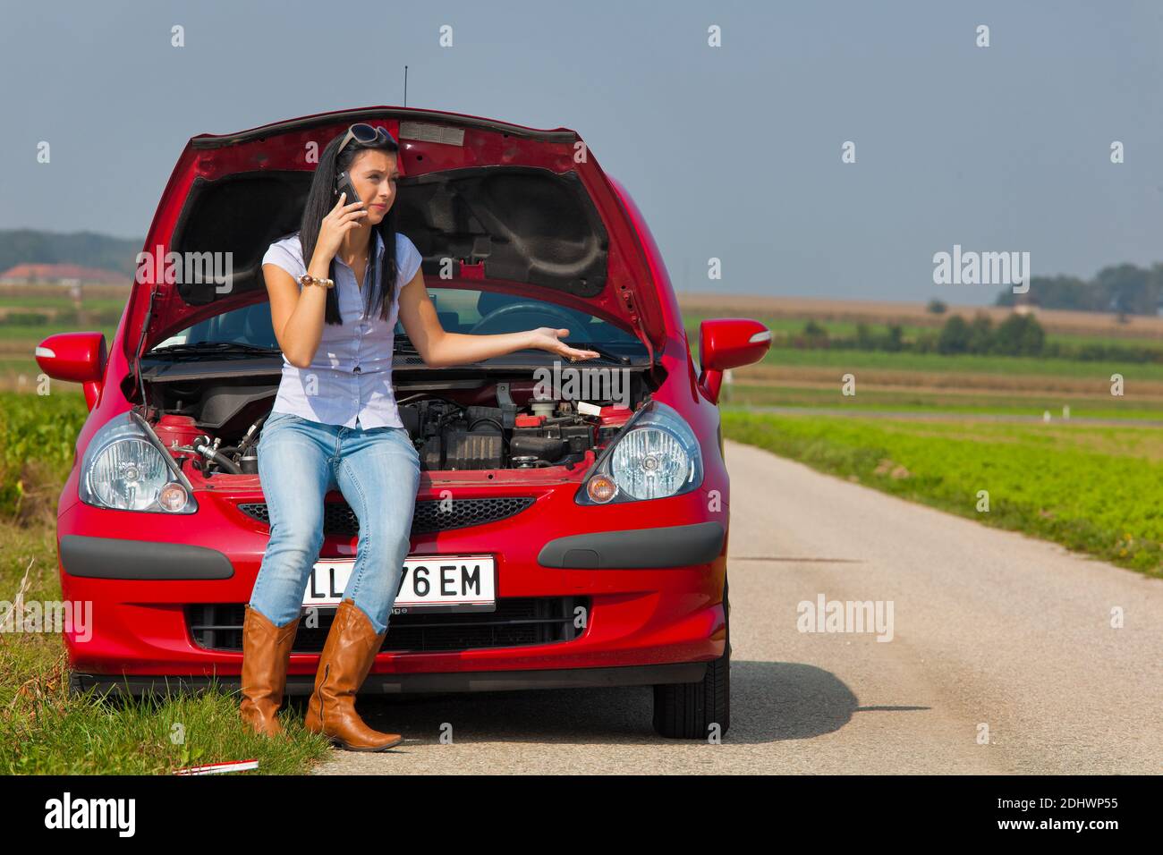 Junge Frau mit einer Motorpanne am Auto Banque D'Images