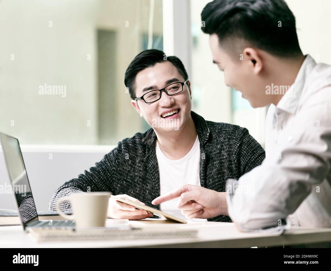 deux jeunes entrepreneurs asiatiques discutant des affaires au bureau en utilisant le numérique tablette et ordinateur portable Banque D'Images