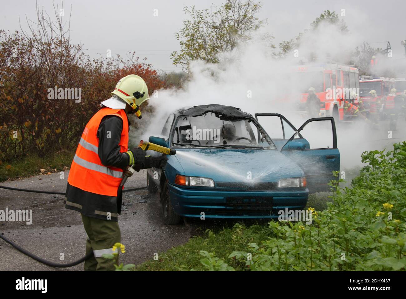 Feuerwehr loescht ein brennendes Auto, Verkehrsunfall, Banque D'Images