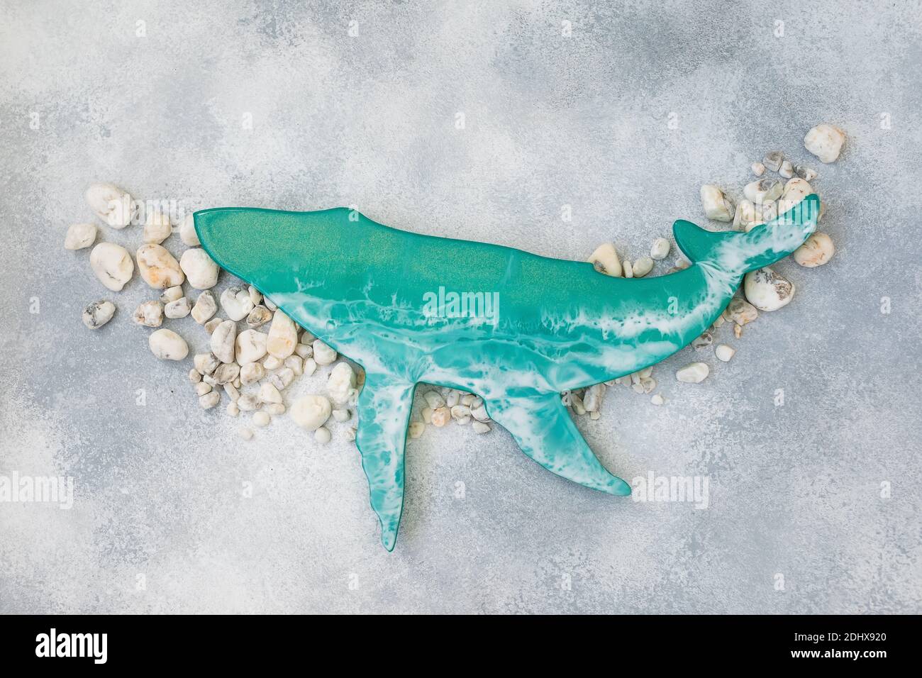 Baleine d'art en résine avec vagues de tissu et coquillages sur fond gris. Pose à plat Banque D'Images