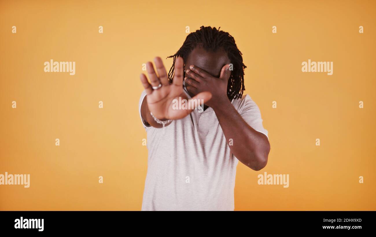 Arrêter. Le jeune homme noir afro-américain tient la main sur les yeux et montre s'arrêter avec son autre main. Photo de haute qualité Banque D'Images