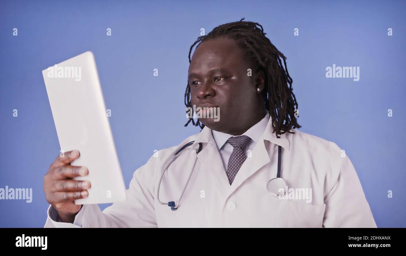 Jeune homme noir afro-américain utilisant une tablette pour la recherche médicale. Photo de haute qualité Banque D'Images