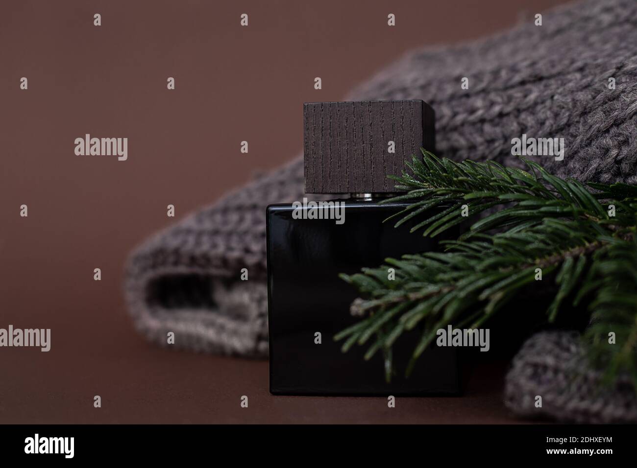 Parfum, parfum ou flation pour hommes après un rasage sur fond marron à côté d'un chandail et aiguilles pour hommes, épinette, luxe, cadeau. Gros plan photo pour Banque D'Images