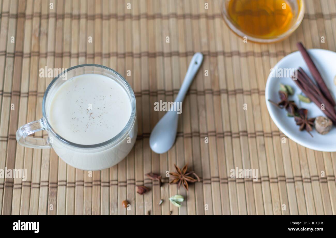 Thé masala dans une tasse de verre avec épices et miel sur fond de bois. Boisson indienne. Orientation horizontale. Copier l'espace. Banque D'Images