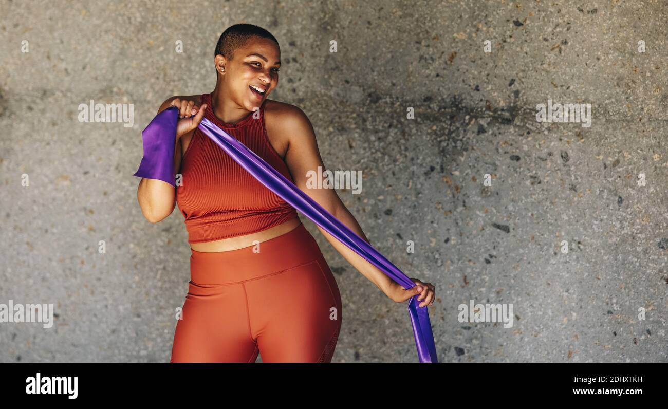 Une femme plus grande taille s'entraîner avec un bracelet de résistance. Bonne femme en forme physique tenue d'exercice à l'extérieur. Banque D'Images