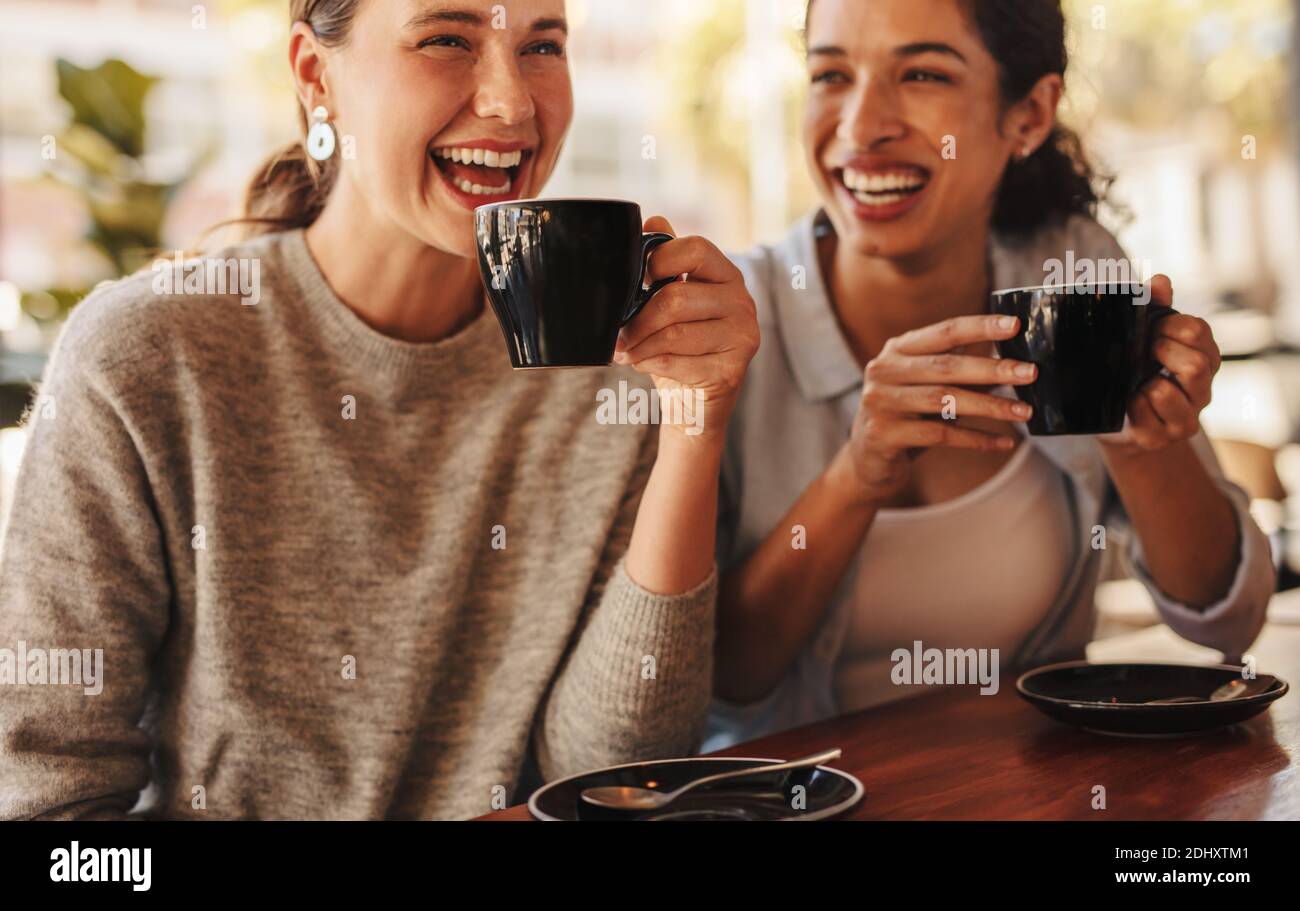Deux amis prenant un café ensemble dans un café-restaurant. Les meilleurs amis se sont fait des potins sur le café dans un café. Banque D'Images