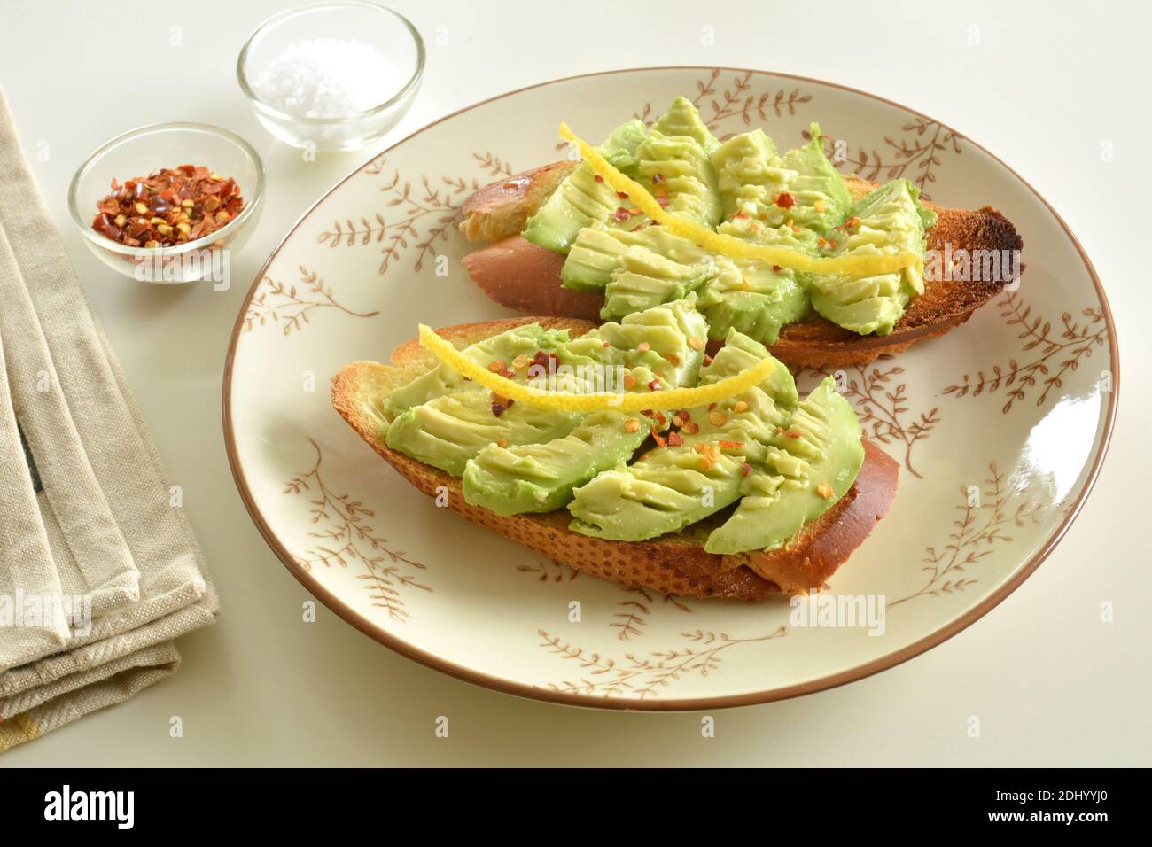 Délicieux toasts végétariens à l'avocat avec jus de citron, sel de mer et flocons de poivre rouge en format horizontal. Banque D'Images
