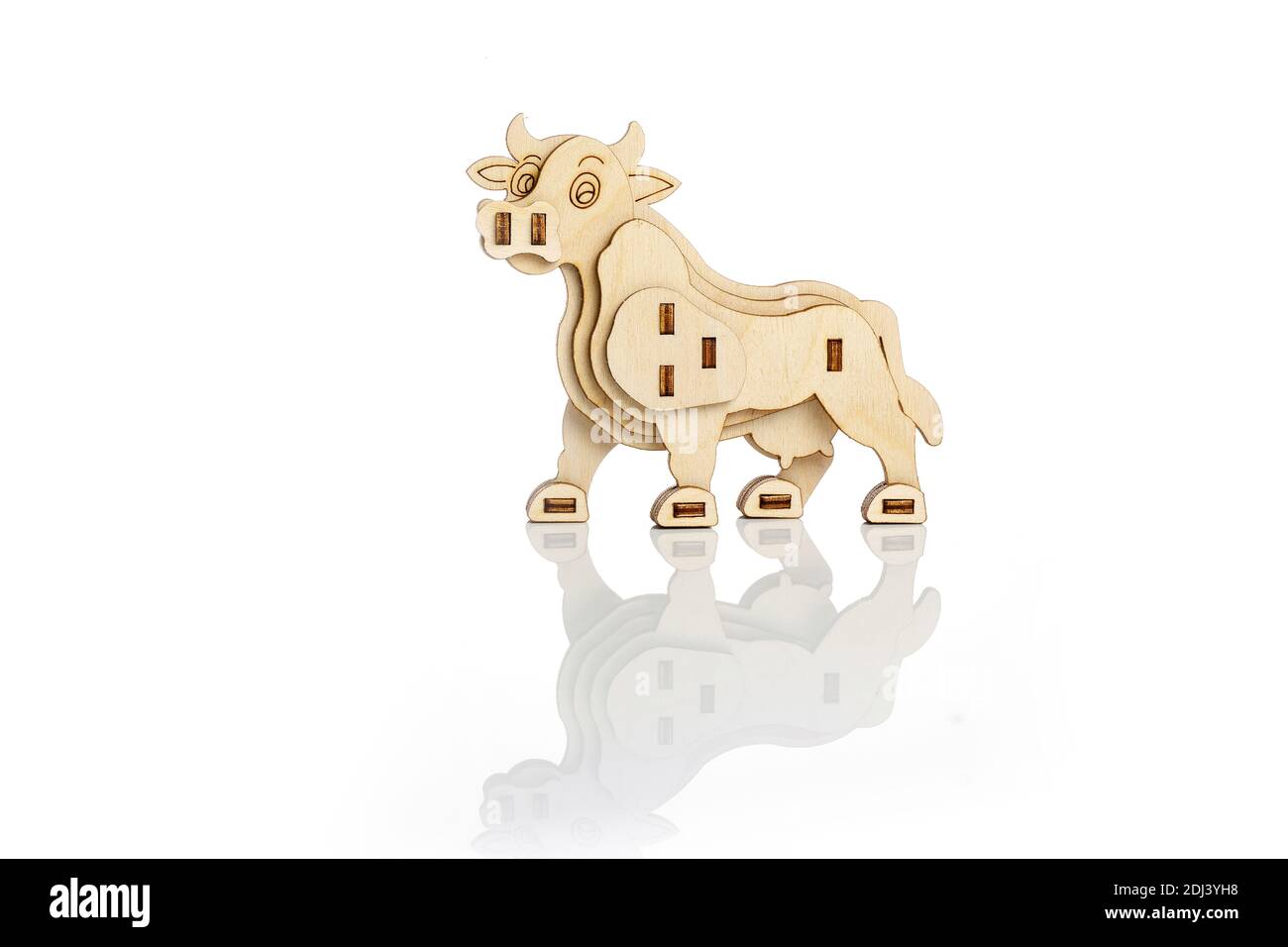 Figurine d'une vache en bois sur fond blanc avec réflexion Banque D'Images