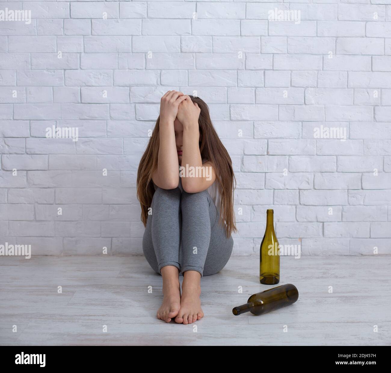Alcoolisme et dépression concept. Une jeune femme pleure sur le sol à la  maison avec des bouteilles vides autour d'elle Photo Stock - Alamy