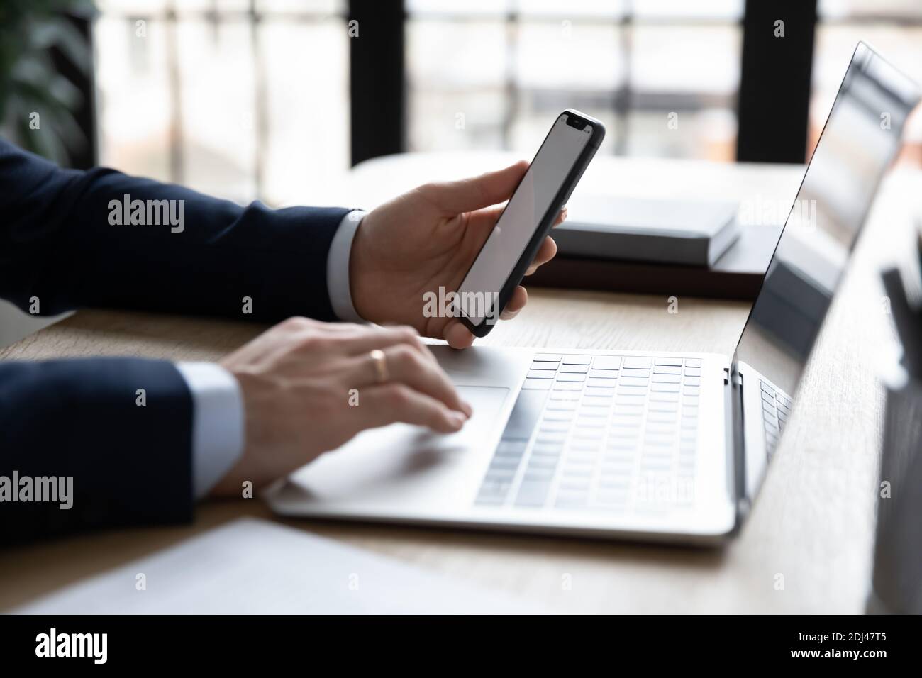 Homme d'affaires proche utilisant le téléphone et l'ordinateur portable, travaillant en ligne Banque D'Images
