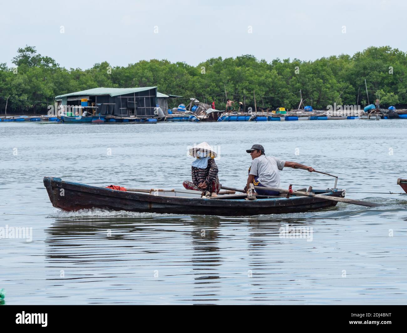 Petit bateau à moteur avec deux personnes descendant la rivière Dinh près de Vung Tau dans la province de Bang Ria-Vung Tau, au sud du Vietnam. Banque D'Images