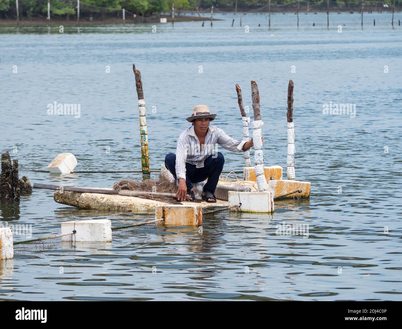 Pêcheur qui tend à ses filets à partir d'un radeau en mousse de polystyrène sur la rivière Dinh près de Vung Tau dans la province de Bang Ria-Vung Tau, au sud du Vietnam. Banque D'Images