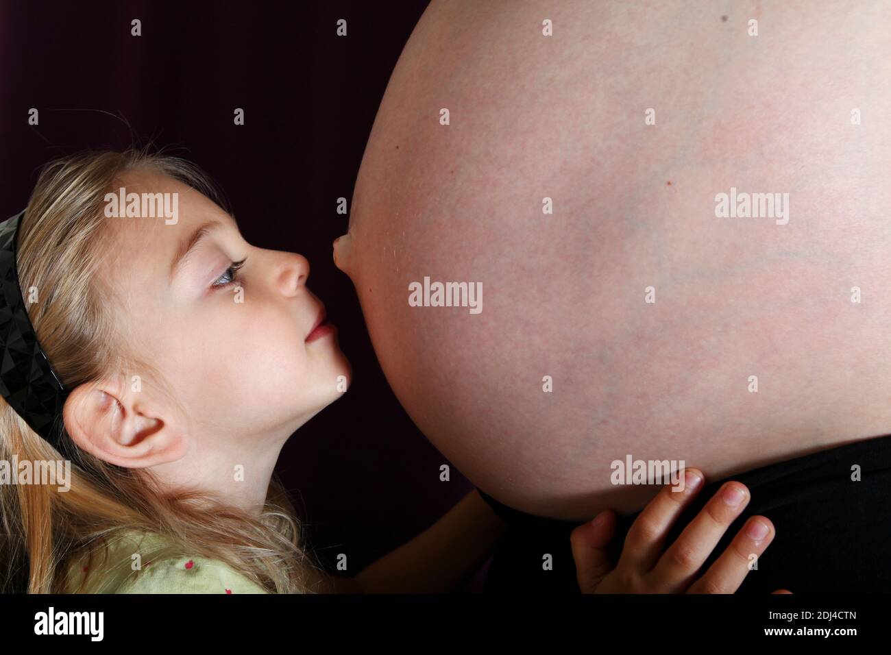 une jeune fille embrasse le ventre de sa mère Banque D'Images