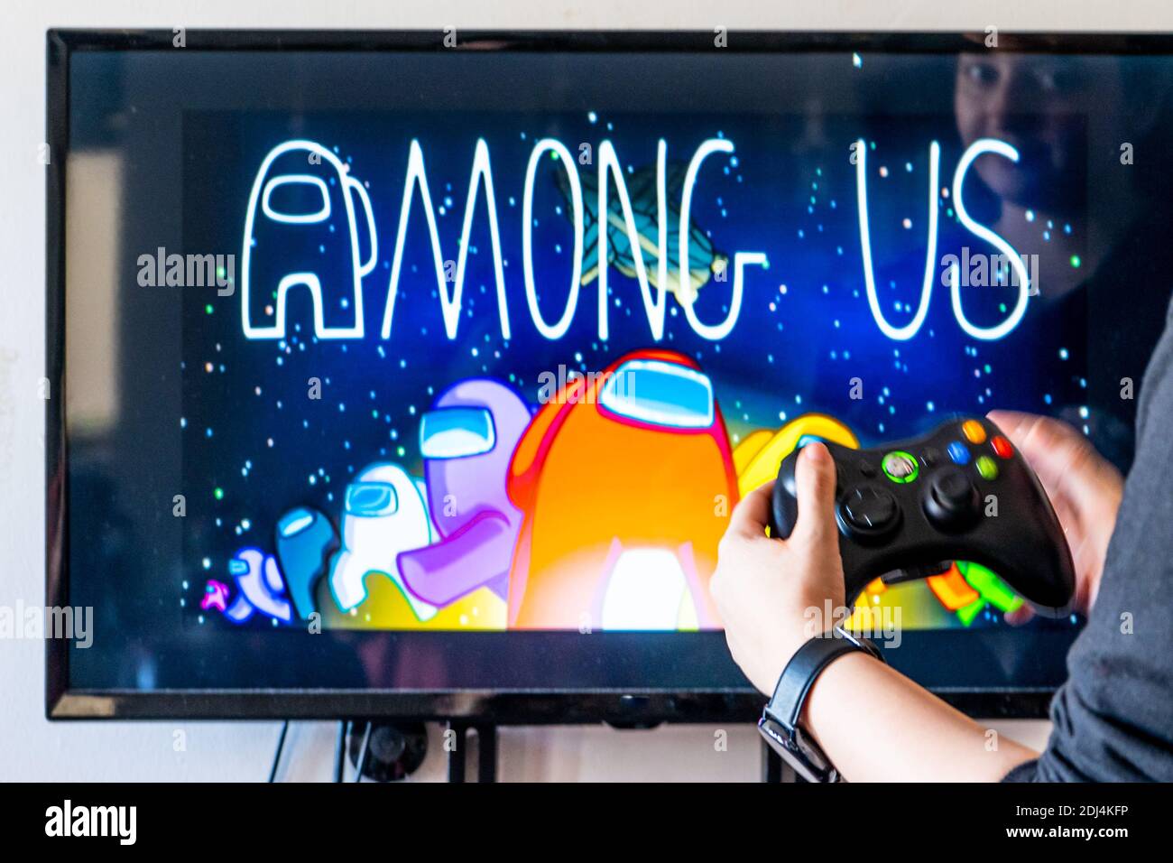 Femme tenant une manette xbox et jouant à un jeu vidéo populaire Parmi nous sur un téléviseur et un PC Banque D'Images