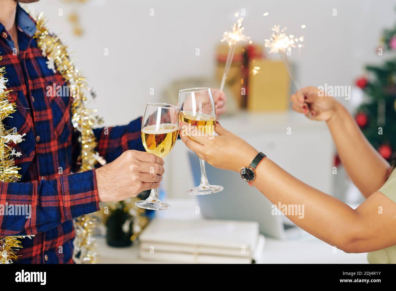 Mains de collègues brûlant des lumières du Bengale et toaster avec du champagne Lunettes pour célébrer le nouvel an au bureau Banque D'Images