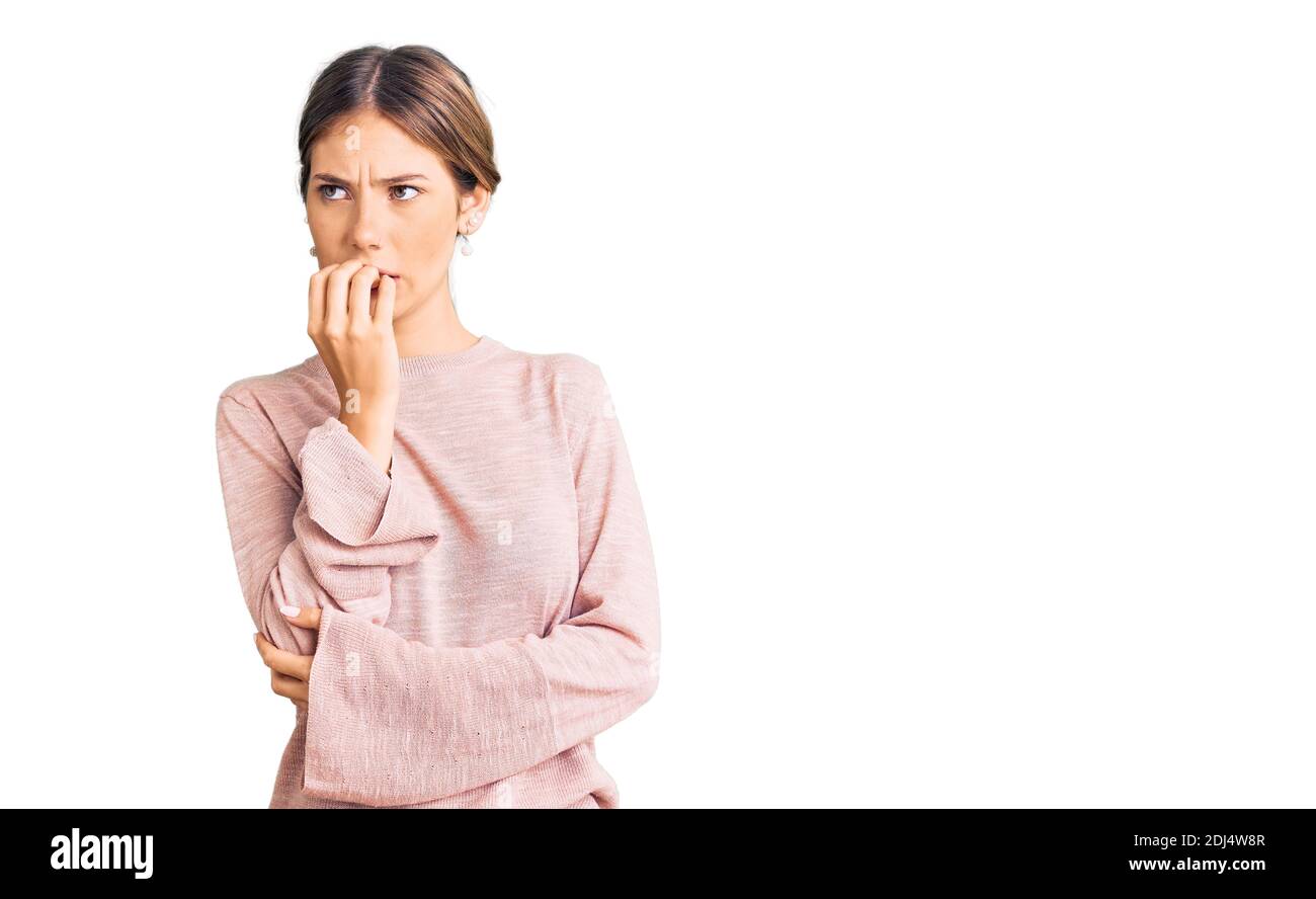 Belle femme caucasienne avec cheveux blonds portant décontracté hiver chandail regardant stressé et nerveux avec les mains sur la bouche mordant des ongles. Anxiété proble Banque D'Images