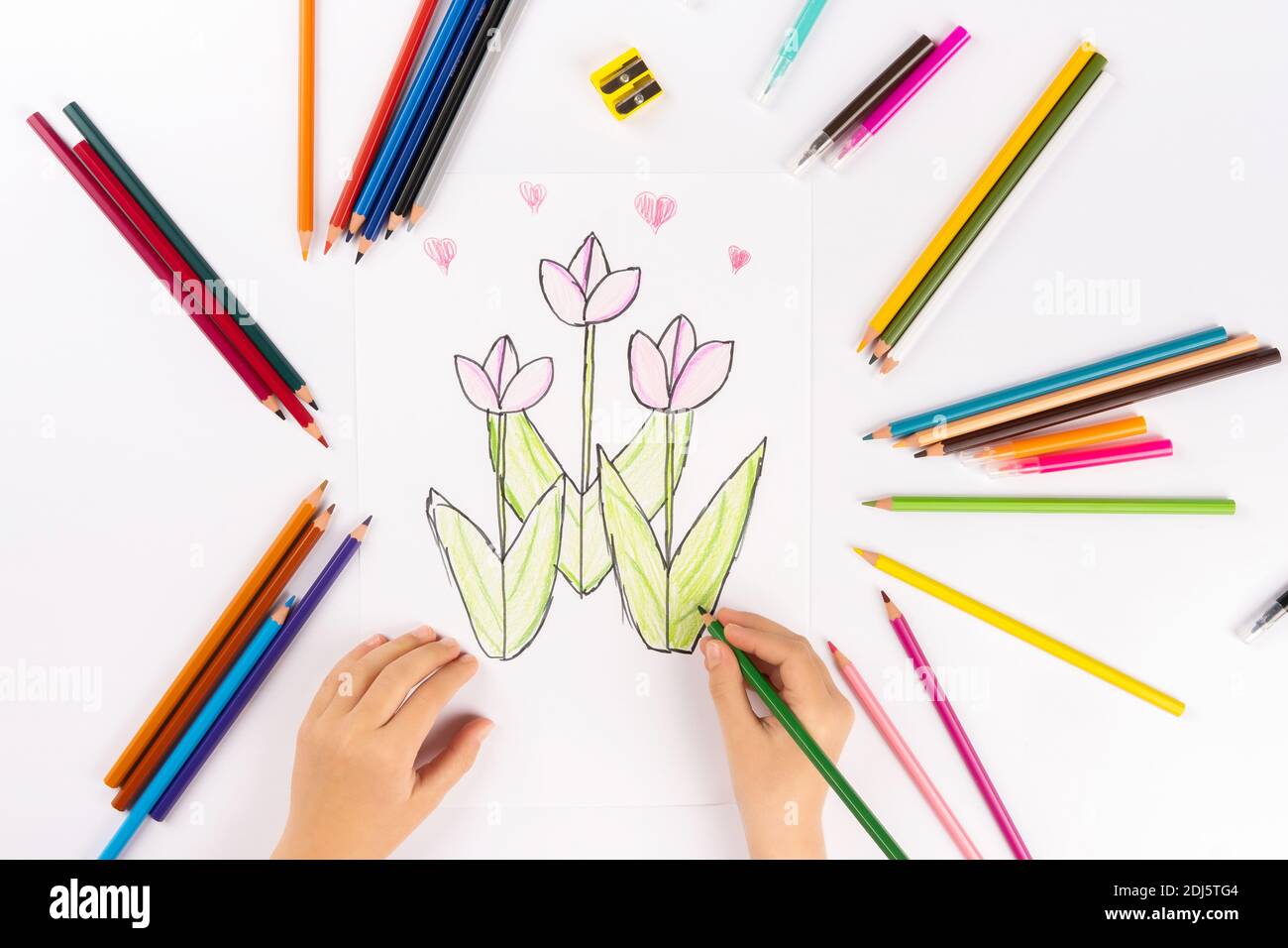 Enfant fille dessine des fleurs sur une feuille blanche. Banque D'Images