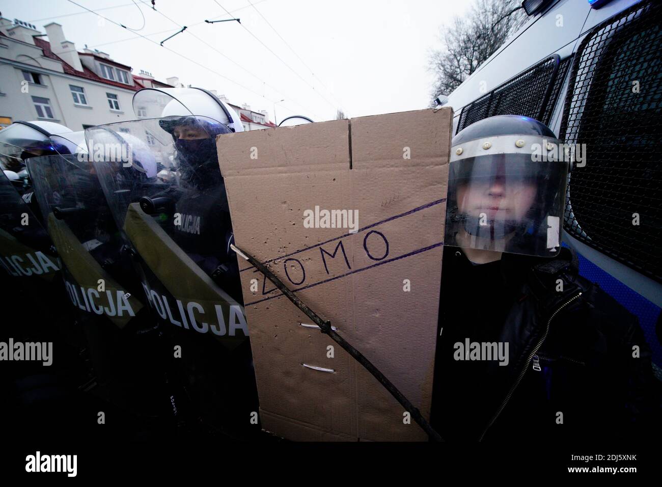 Le 13 décembre 202, un jeune manifestant tient un bouclier de carboard portant le nom de la célèbre force paramilitaire SOVIÉTIQUE ZOMO à Varsovie, en Pologne Banque D'Images