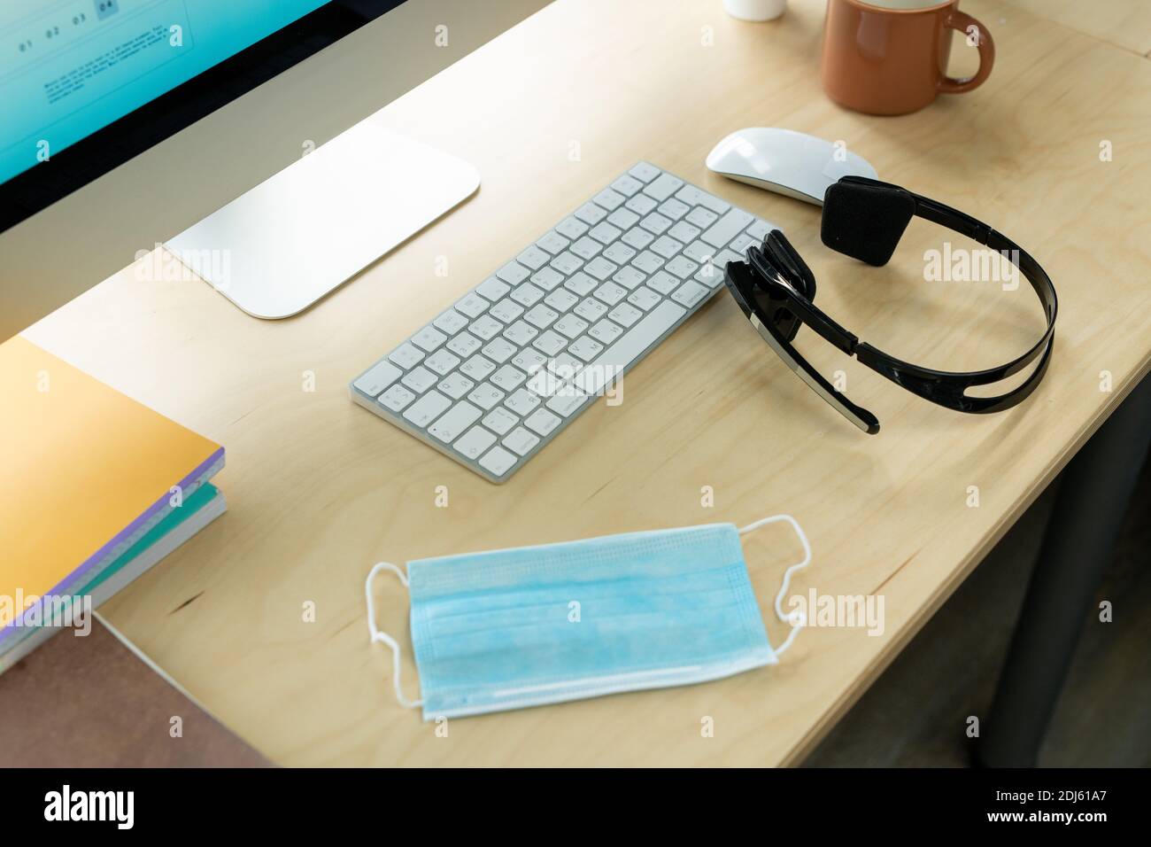 Lieu de travail d'un représentant de l'assistance clientèle moderne avec écran d'ordinateur, clavier, souris, casque, masque et mug avec boisson Banque D'Images