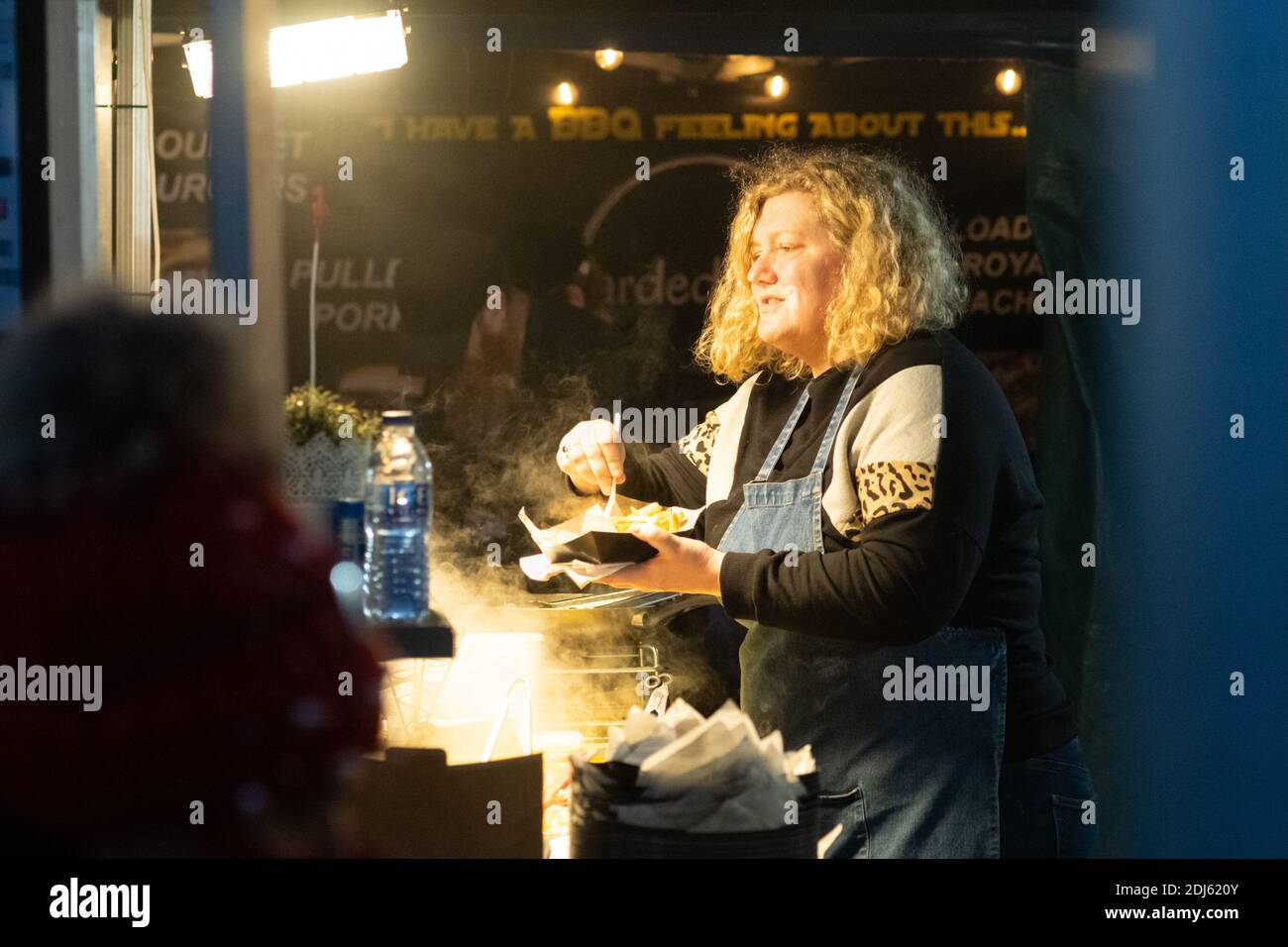 Manchester décembre 2020. Marchés de Noël vendant de la nourriture près de Piccadilly Gardens. Une dame sert des frites à un client Banque D'Images