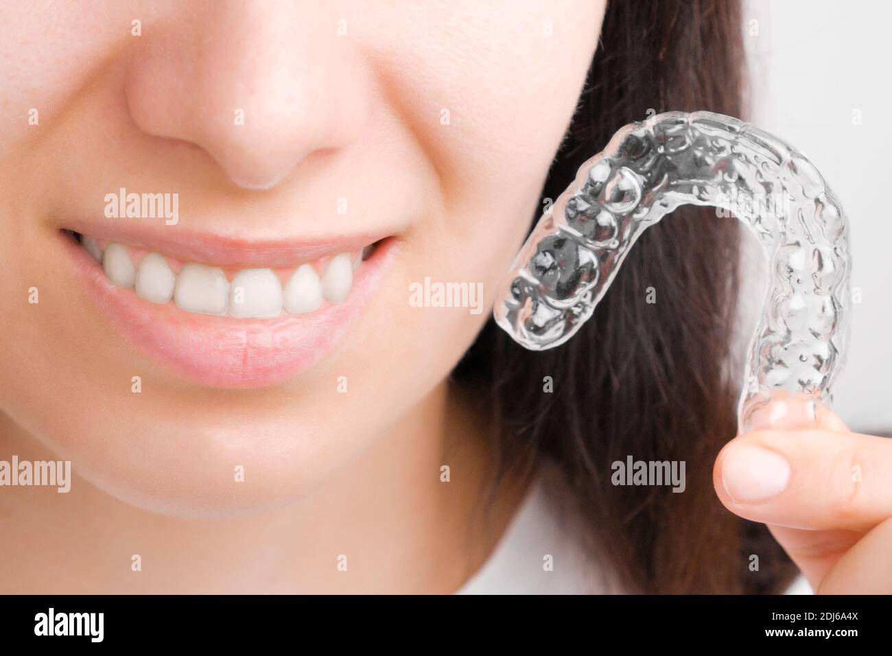 Femme en gros plan tenant une bretelles amovibles transparentes pour un sourire parfait. Aligneurs orthodontiques pour lisser et blanchir les dents. Banque D'Images