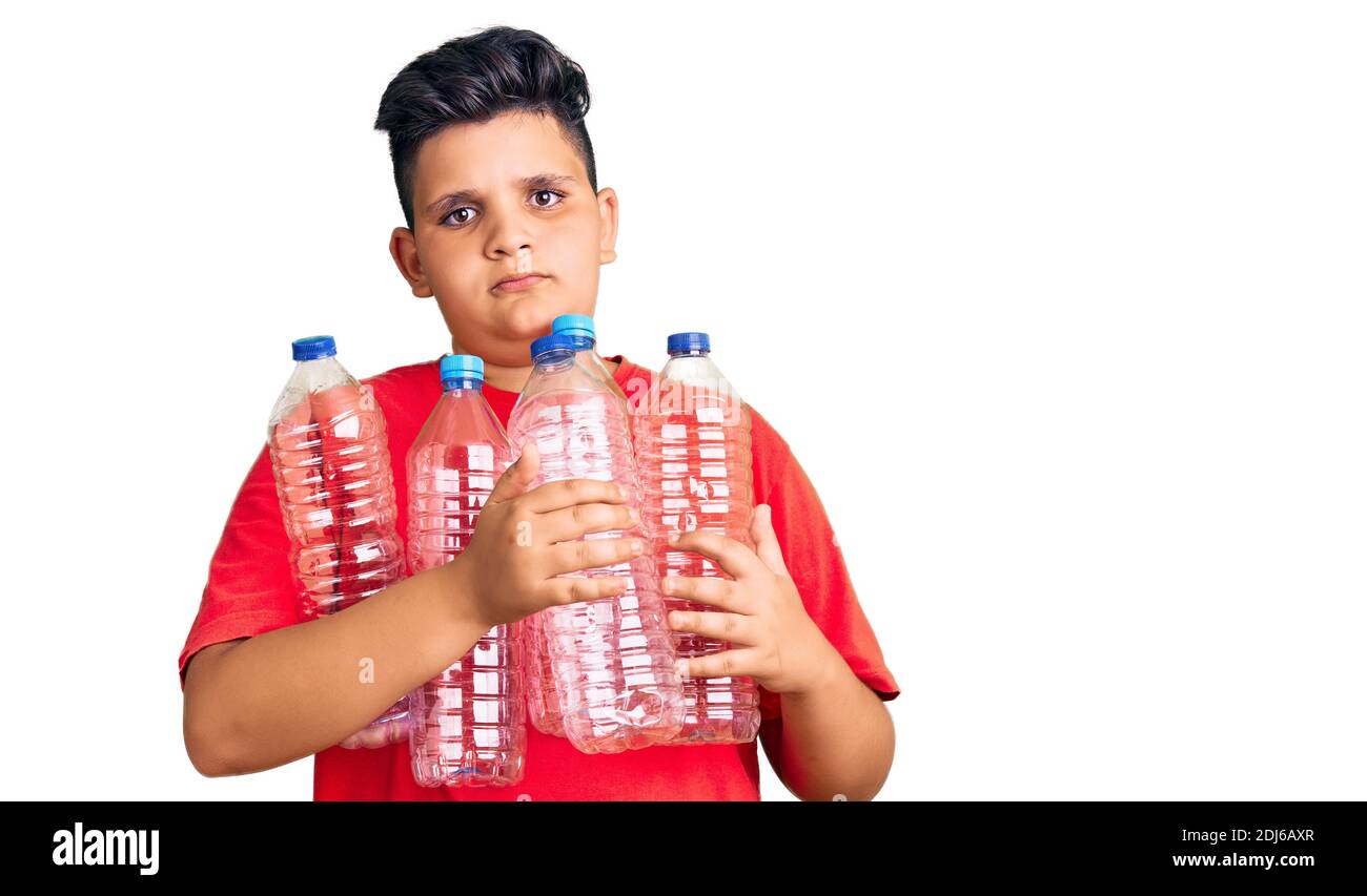Un petit garçon tient des bouteilles en plastique de recyclage pensant attitude et expression sobre et confiance en soi Banque D'Images