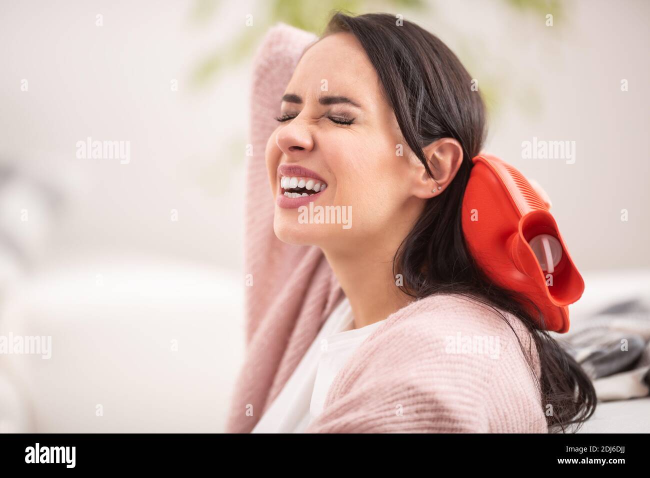 Libération de la douleur au cou par un thermophore par une femme brune. Banque D'Images