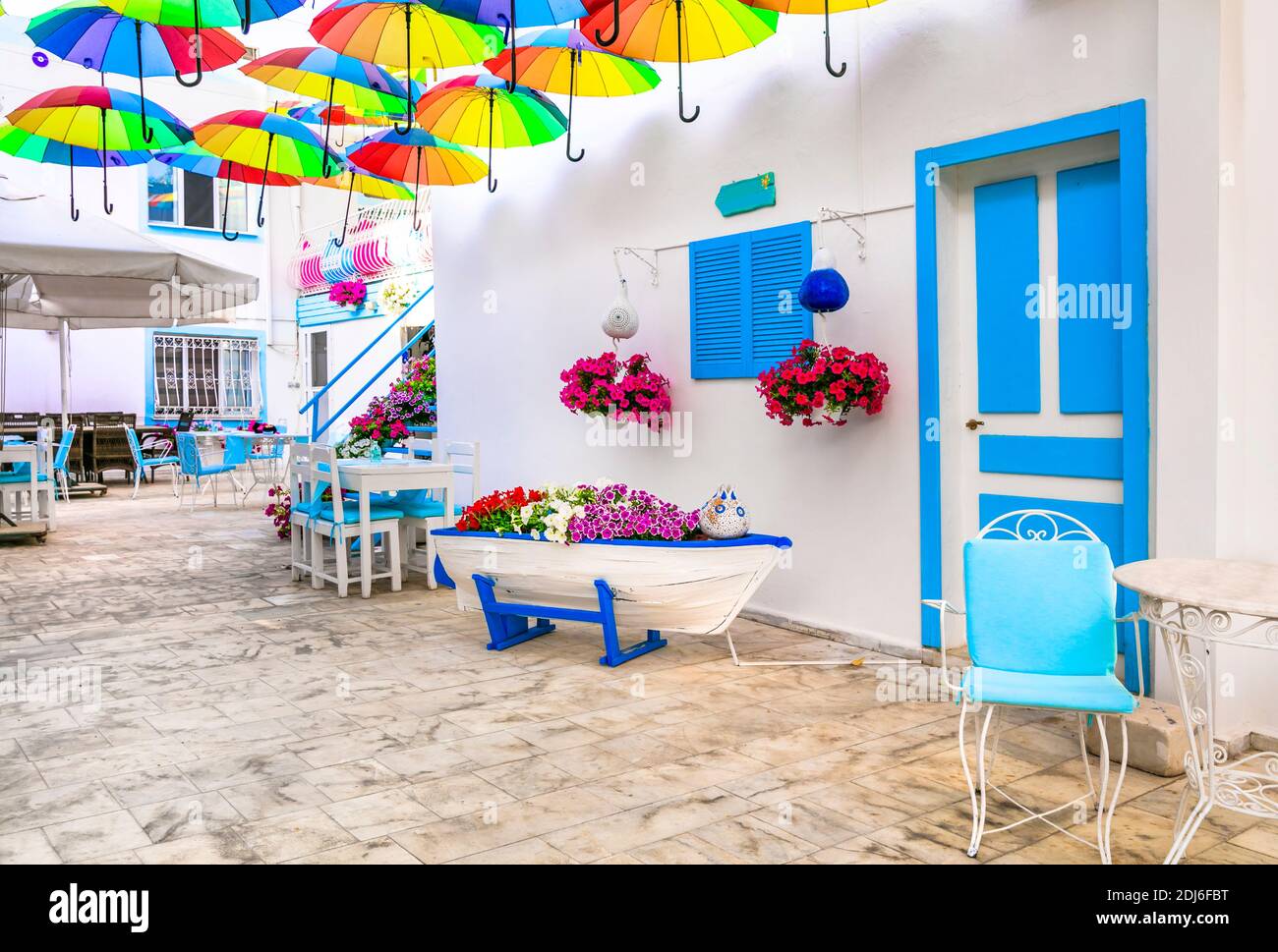 Belle décoration de bar de rue (restaurant) avec parasols colorés, vieux bateau en bois et fleurs. Bodrum, Turquie Banque D'Images