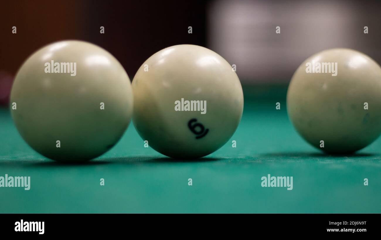 Partie de billard. Boules de billard sur la table. Lumière tamisée dans la salle de billard. Boules blanches sur une surface de table verte. Banque D'Images