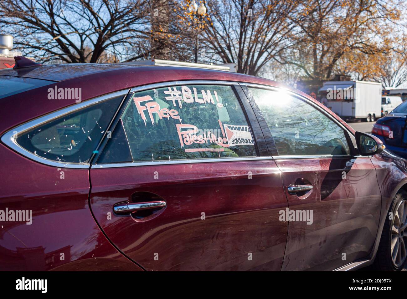 Texte de hashtag 'BLM' et 'Free Palestine' écrit avec de la craie de verre sur une fenêtre de voiture rouge. La voiture est garée près de la Maison Blanche à Washington DC. A p Banque D'Images