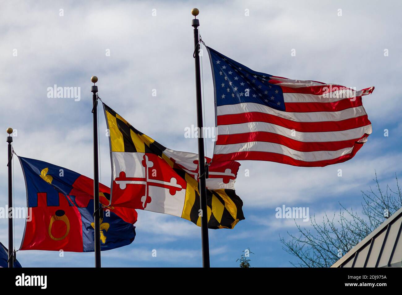 Les treufanions voquent sur des poteaux de drapeaux séparés contre le ciel bleu lors d'une journée venteuse. De droite à gauche, ils représentent : les États-Unis, l'État du Maryland et Montgomer Banque D'Images