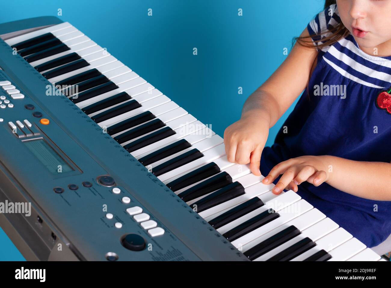 gros plan des mains et des doigts d'une enfant en appuyant sur les touches  d'un piano électronique, leçon de musique isolée sur fond bleu Photo Stock  - Alamy