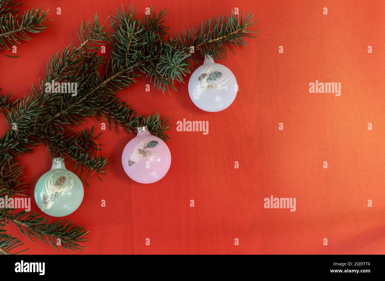 Branches d'arbre de Noël décorées de boules colorées sur fond rouge étincelant. Noël, nouvel an, vacances d'hiver. Banque D'Images