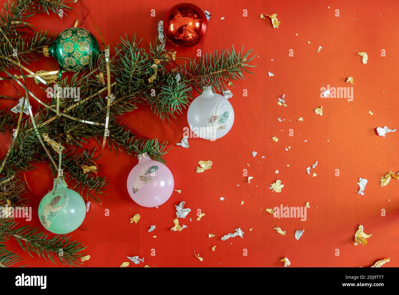 Branches d'arbre de Noël décorées de boules colorées sur fond rouge étincelant. Noël, nouvel an, vacances d'hiver. Banque D'Images