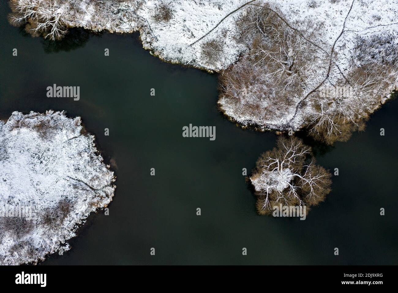 vue aérienne de la berge gelée avec arbres couverts de neige et l'eau sombre Banque D'Images