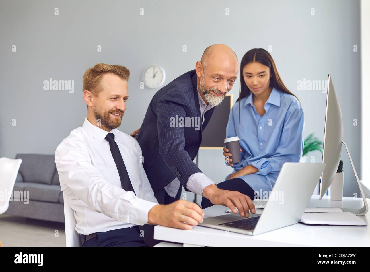 Des employés de bureau heureux utilisant un ordinateur portable pour travailler sur un projet ou pour regarder une vidéo amusante pendant la pause Banque D'Images