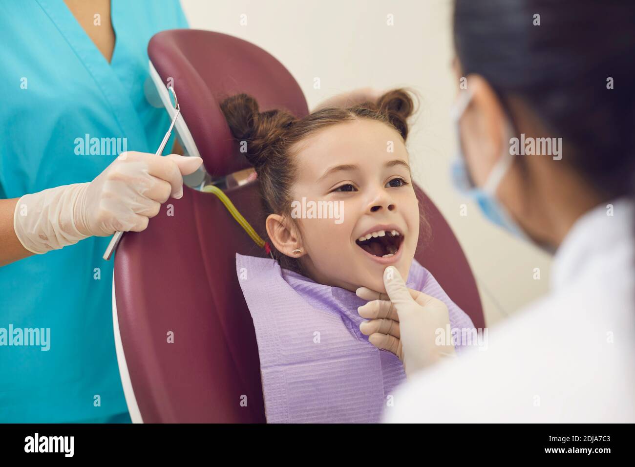 Femme dentiste examinant les dents souriantes des filles dans la bouche ouverte dedans clinique dentaire Banque D'Images