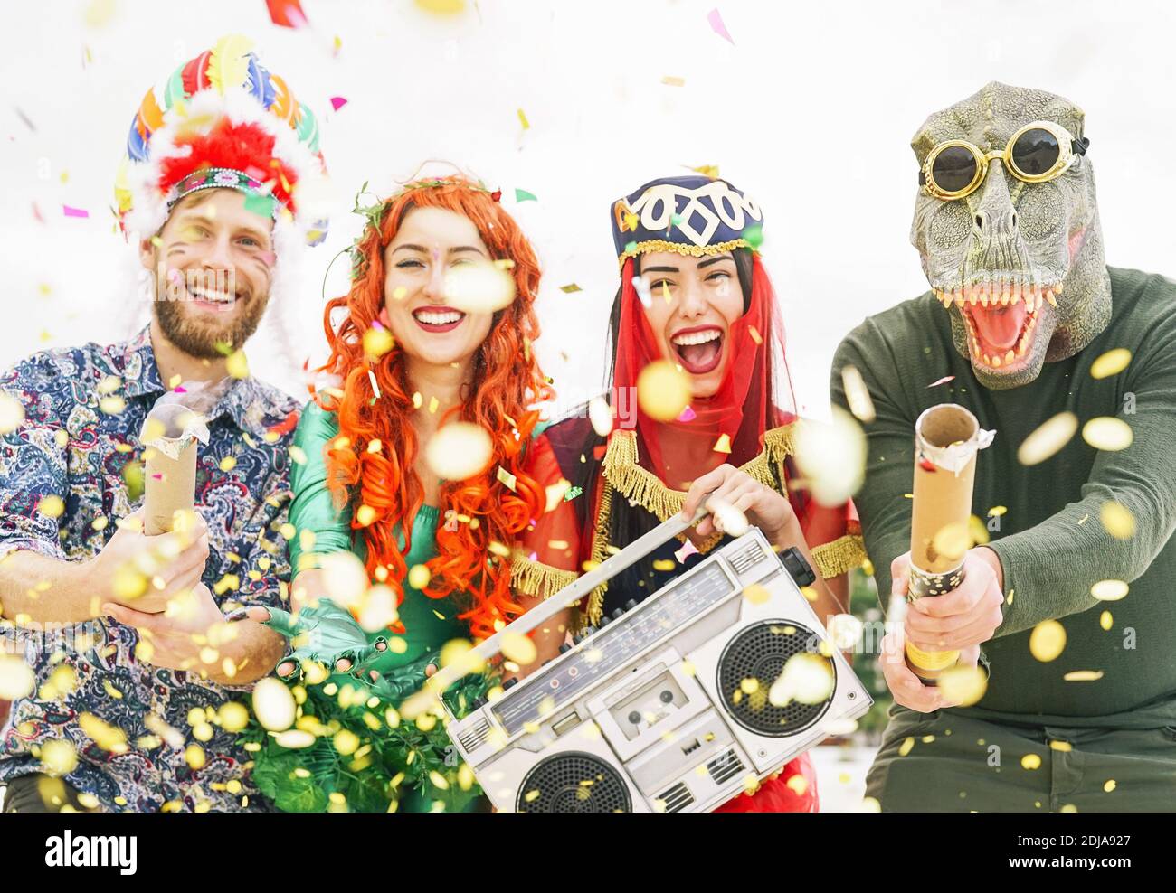 Joyeux amis célébrant l'événement de fête de carnaval en plein air - jeunes fous ayant des costumes amusants à écouter de la musique avec une chaîne stéréo vintage boombox Banque D'Images