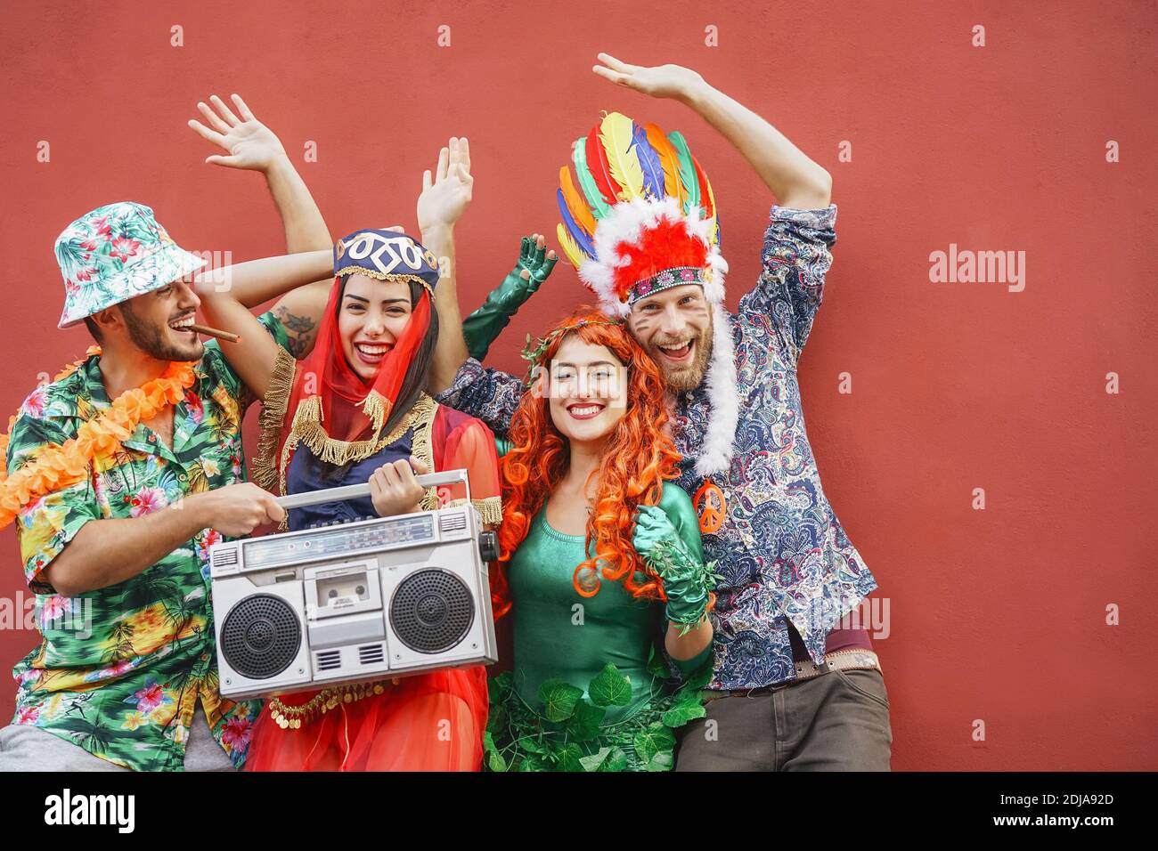 Heureux amis célébrant la fête du carnaval en plein air - jeunes fous ayant des costumes de fantaisie écoutant de la musique avec la chaîne stéréo vintage boombox Banque D'Images