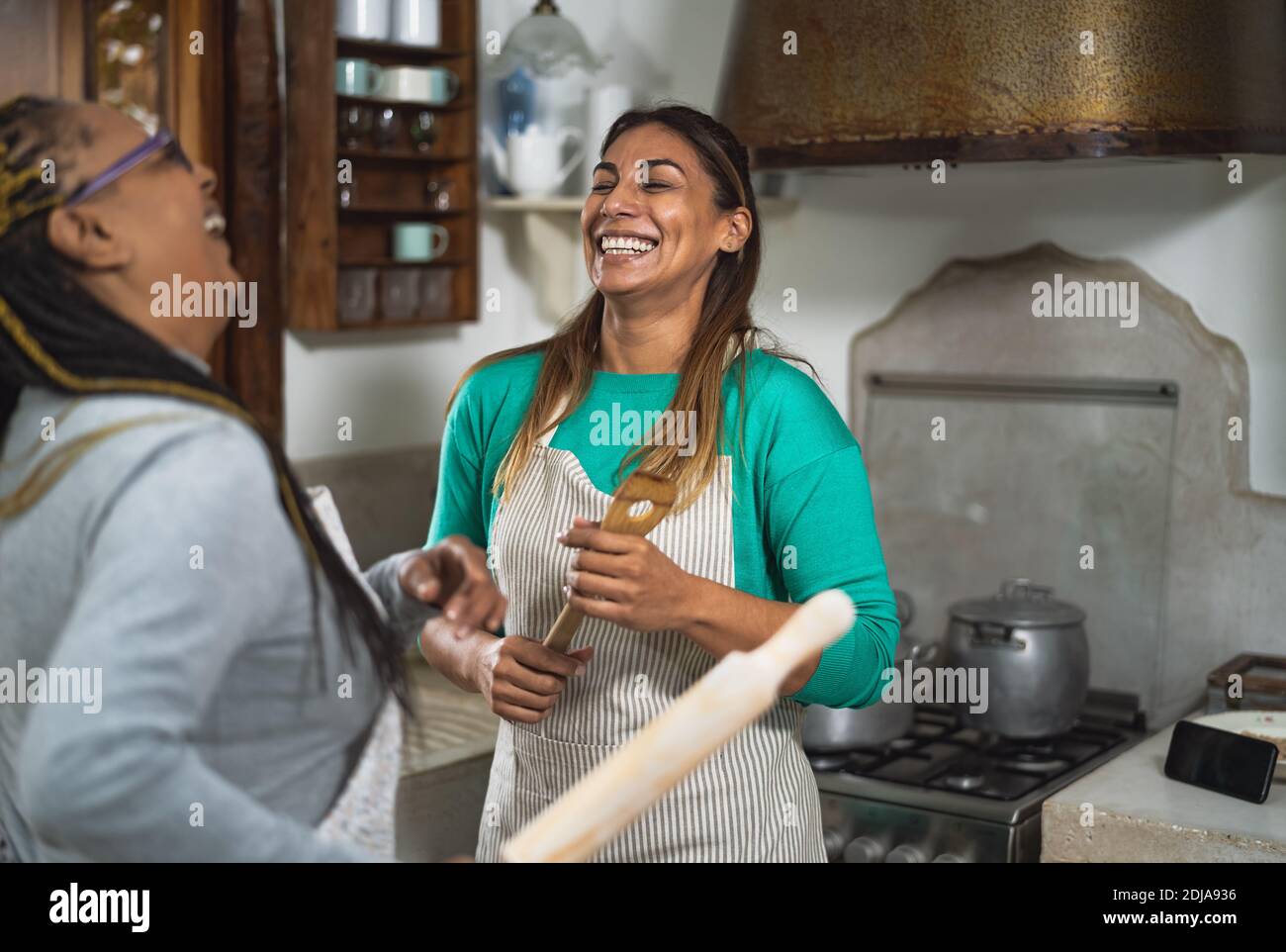 Heureux multiracial femmes ayant du plaisir dans la cuisine de préparer un recette maison dans maison ancienne Banque D'Images