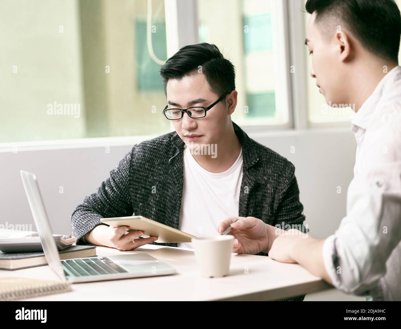 deux jeunes entrepreneurs asiatiques discutant des affaires au bureau en utilisant le numérique tablette et ordinateur portable Banque D'Images
