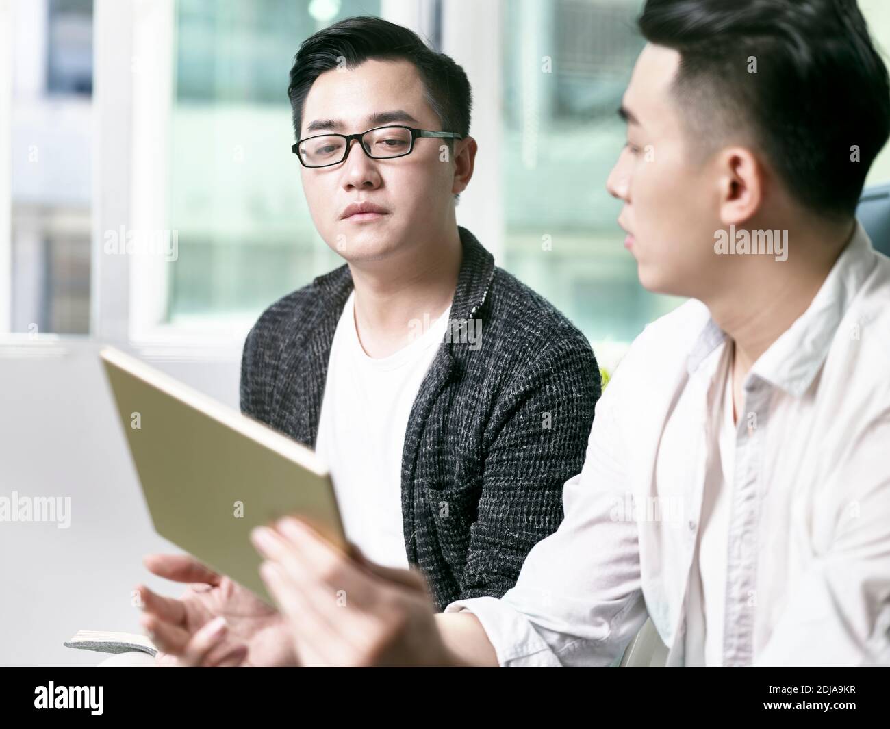 deux jeunes entrepreneurs asiatiques discutant des affaires au bureau en utilisant le numérique tablette Banque D'Images