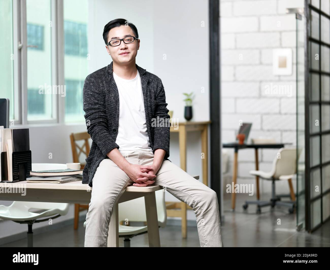 portrait d'un jeune homme d'affaires asiatique assis au bureau regarder l'appareil photo sourire Banque D'Images