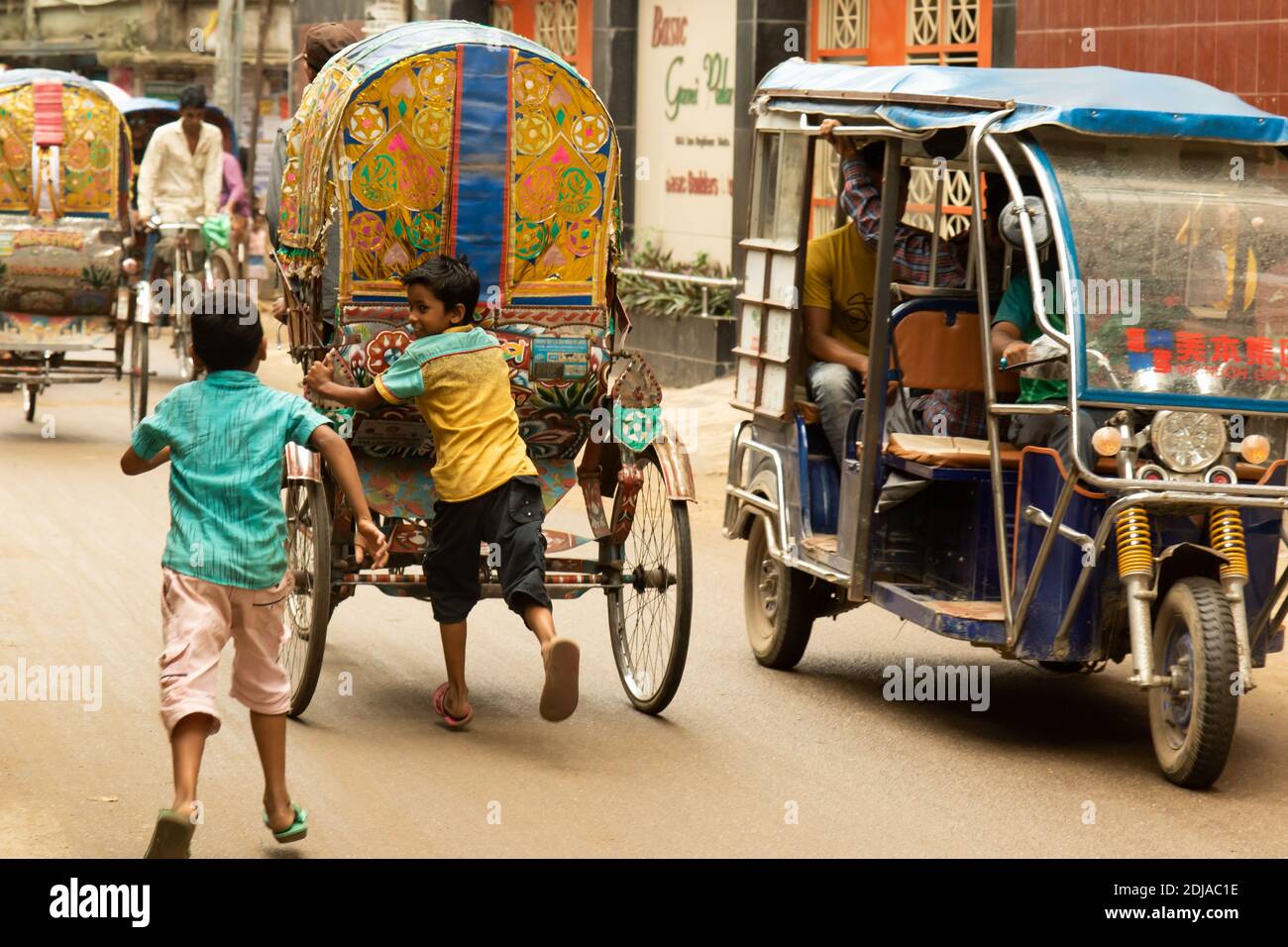 Dhaka, Bangladesh - 28 octobre 2018 : deux enfants jouant et essayant de monter à bord d'un pousse-pousse, le moyen de transport urbain le plus courant. Banque D'Images