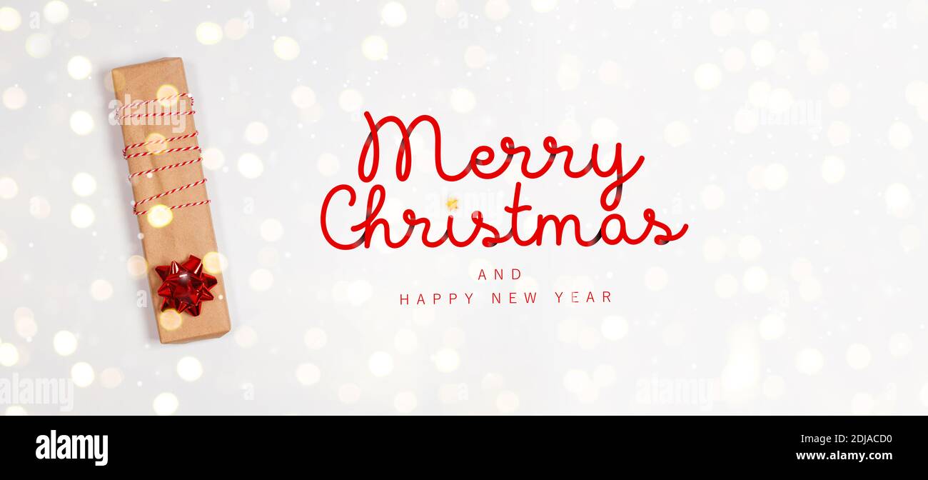 Boîte cadeau, rouleaux de papier d'emballage et décoration claire avec texte Joyeux Noël sur fond blanc. Banque D'Images