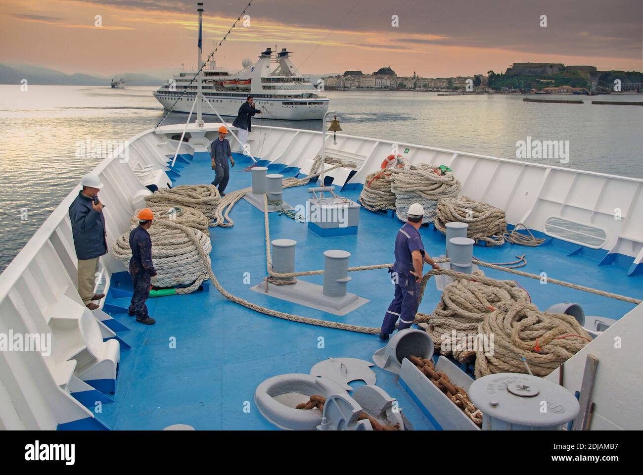 Marin de la marine marchande et gens de mer qui travaillent l'arc du navire de croisière l'équipage du pont-doublure passe la corde d'amarrage de l'aubélier jusqu'au port Jetty dockers grec île de Corfou Banque D'Images